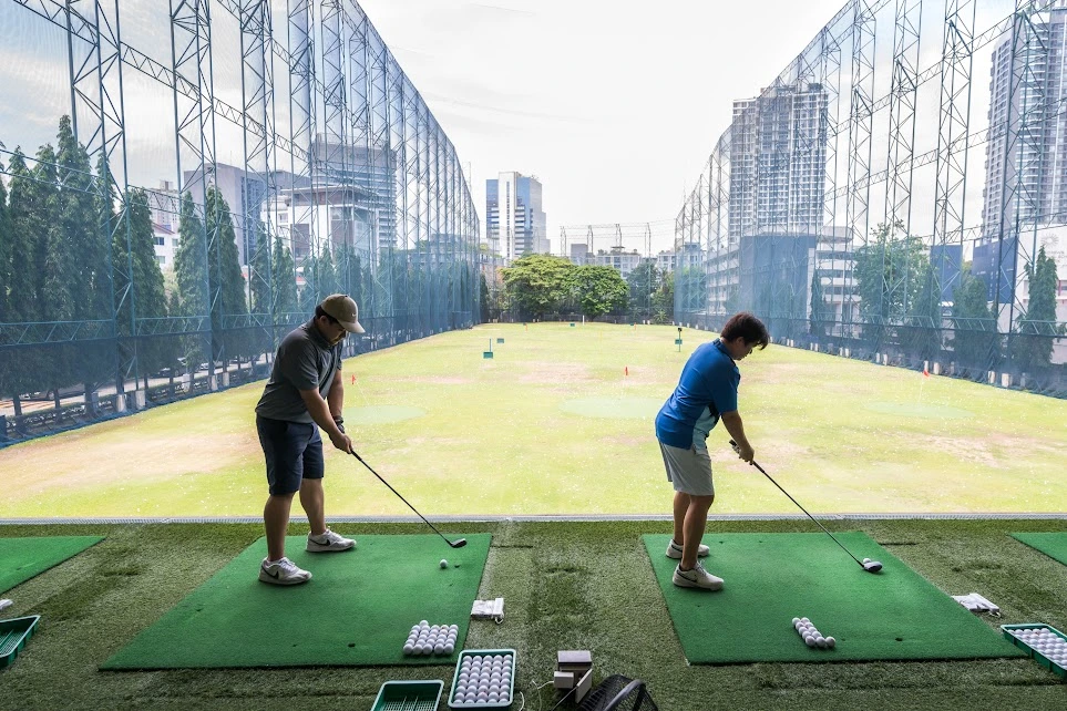 Golfer hitting balls from a practice tray at 42 Tee-Off Golf Driving Range. 